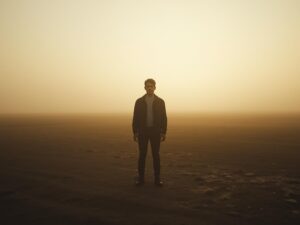 Cinematic photograph of a person standing still in an open landscape at dawn, not moving forward but simply present.